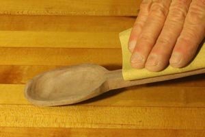 Hand sanding the wooden spoon.